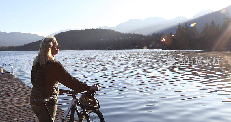 日出时分，女人沿着湖边的码头骑自行车