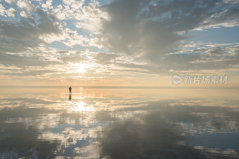 年轻的旅行者在日落时分漫步在盐湖上