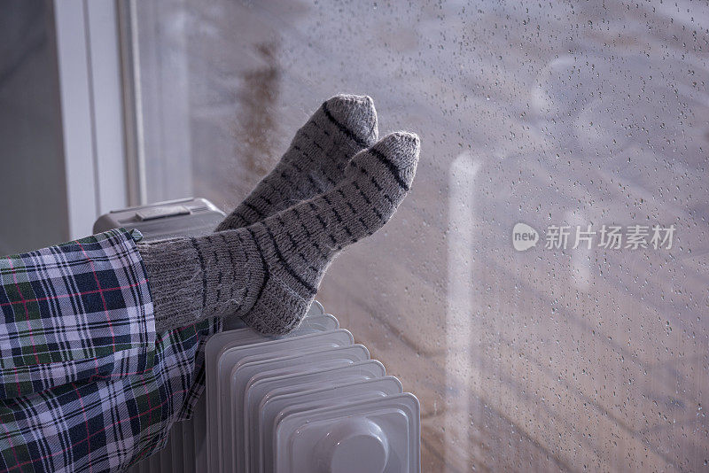 近距离图像的女人的脚散热器加热器在雨季的冬天。