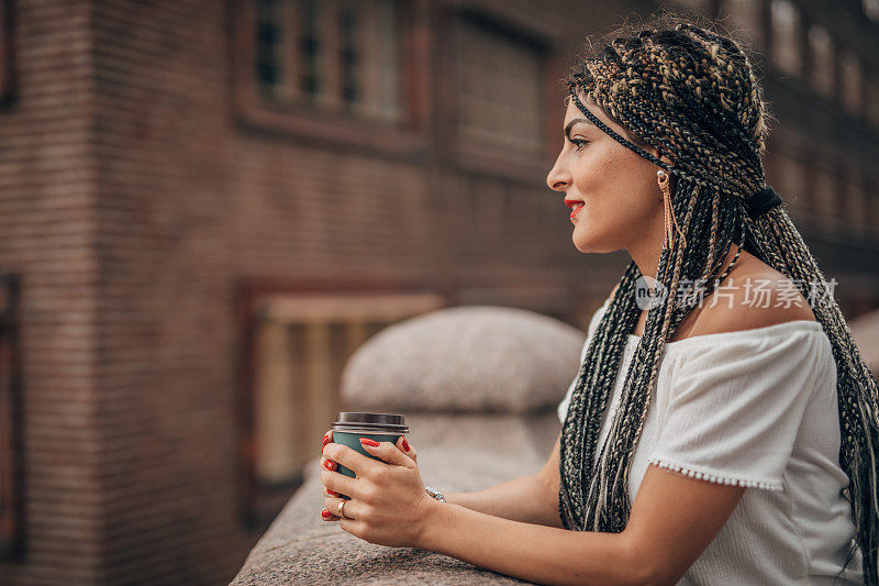 一个年轻女人在市中心的大街上喝咖啡休息