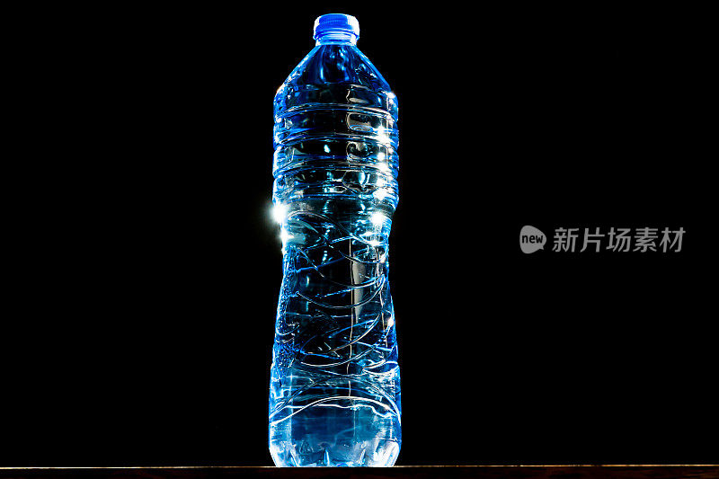 闪亮的蓝色透明塑料瓶上的黑色背景