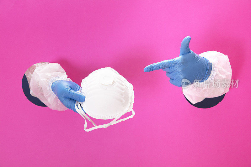 手持医用手套的双手戴着白色口罩，抵御冠状病毒。