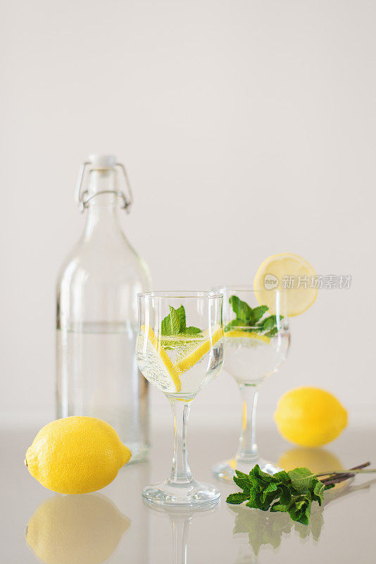 玻璃桌上放一瓶矿泉水和两杯加柠檬和薄荷的苏打饮料。柑橘柠檬水