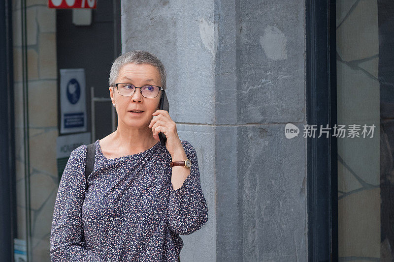 成熟的女人在街上用手机说话