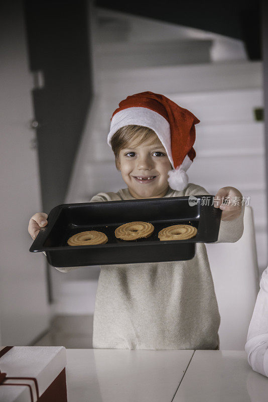 快乐小孩给圣诞老人做了圣诞饼干。圣诞老人的小帮手，快乐家庭的可爱男孩在厨房烤饼干