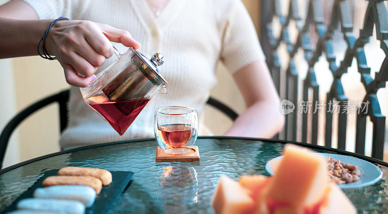 在阳台上倒着茶和零食的女人