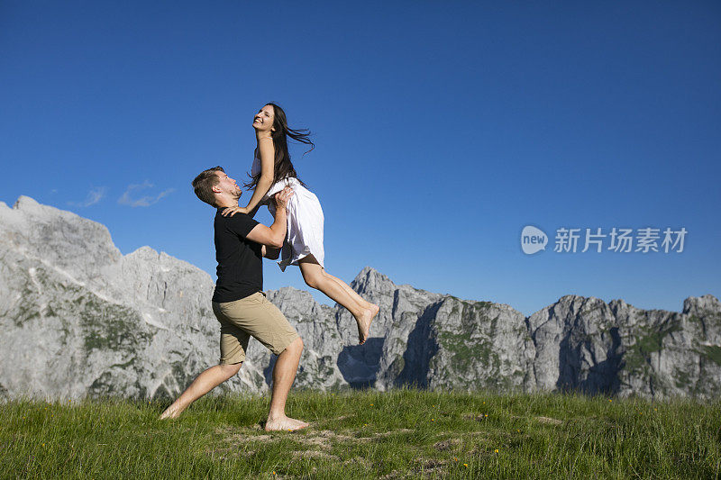 男朋友在山上的草地上捉快乐的女朋友