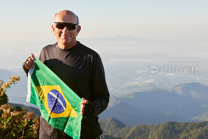 巴西登山家在山顶举着国旗