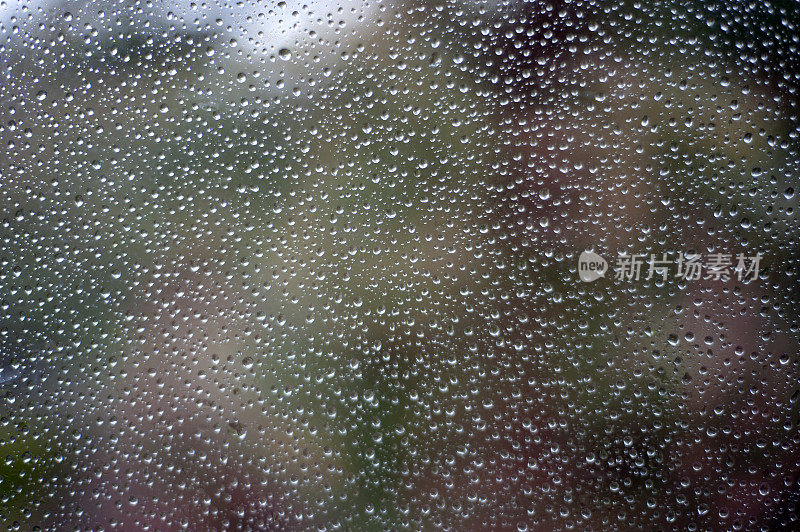 阵雨时聚集的雨滴落在玻璃上