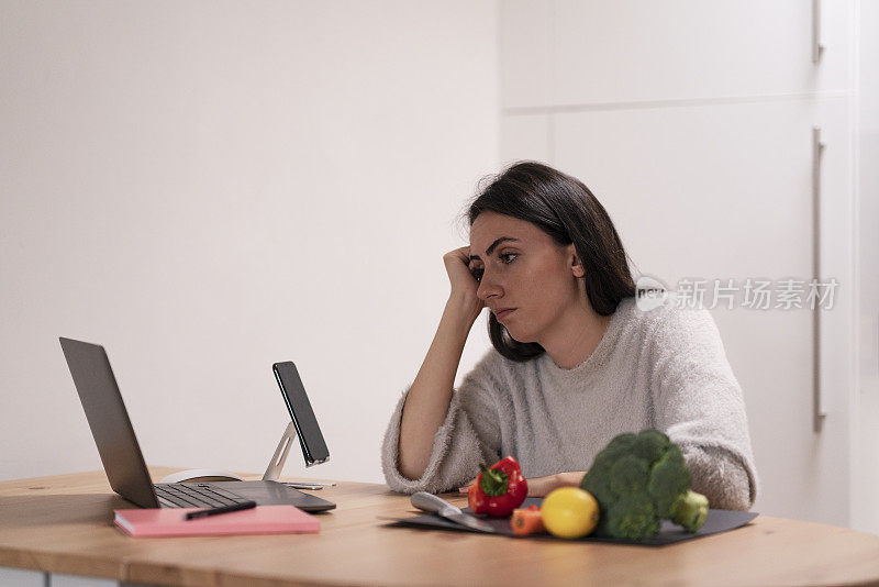 失望而悲伤的女人正在家里看她的笔记本电脑