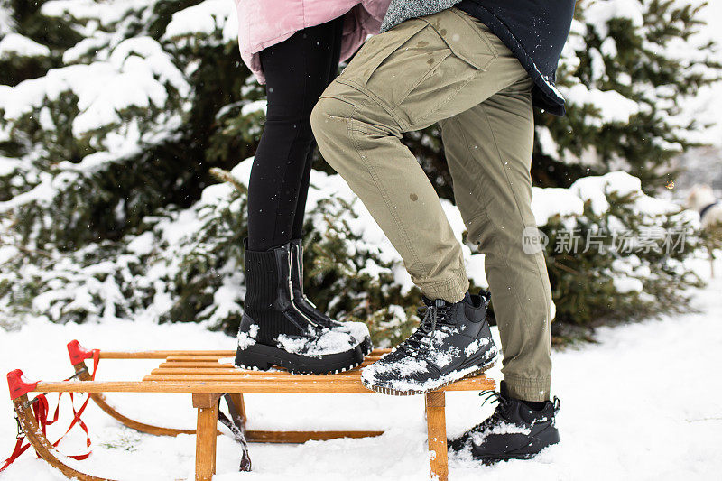 一对夫妇站在雪橇上，腰部以下