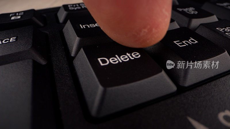 人的手指按下黑色键盘上的删除键