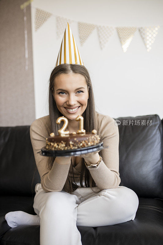 年轻漂亮的女人在家里用巧克力蛋糕庆祝她21岁的生日