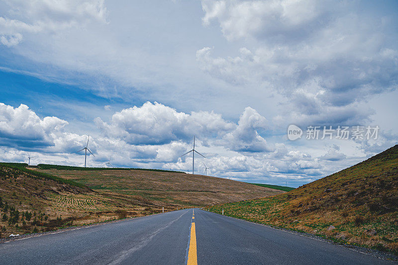 在风力发电机下的草原山间公路