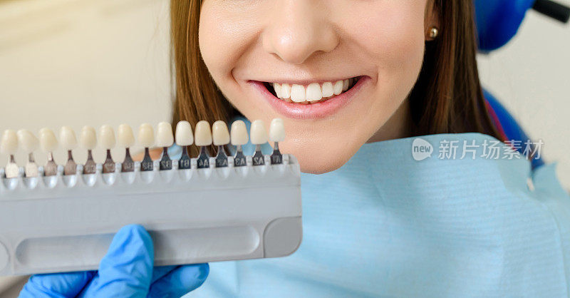 牙医正在根据病人牙齿的颜色表检查牙齿的颜色
