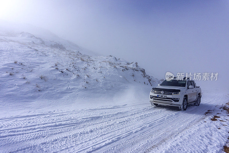在土耳其安塔利亚，一辆白色小货车在雾天的雪地上行驶