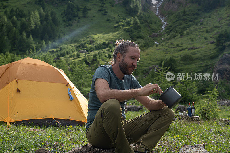 一名男性徒步旅行者在营地旁准备午餐