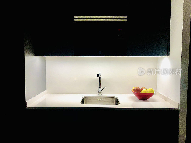 一个设计厨房的洗碗机区域的前视图，碗和苹果在一边。