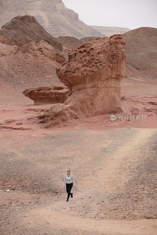 在沙漠峡谷和岩石之间行走的女人