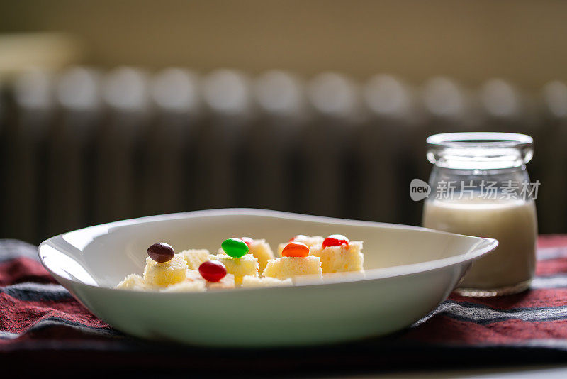 早餐有一杯牛奶和麦片，上面装饰着五颜六色的软糖。孩子们的早餐小吃