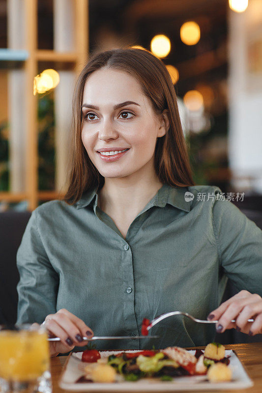 一个漂亮的女孩在餐厅里喝着白(红)酒吃饭。