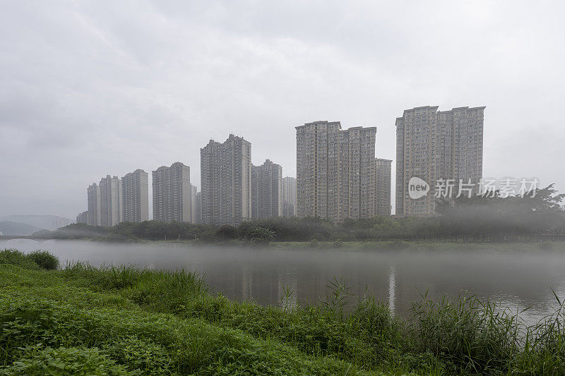 晨雾中的城市映衬着湖边的高楼大厦