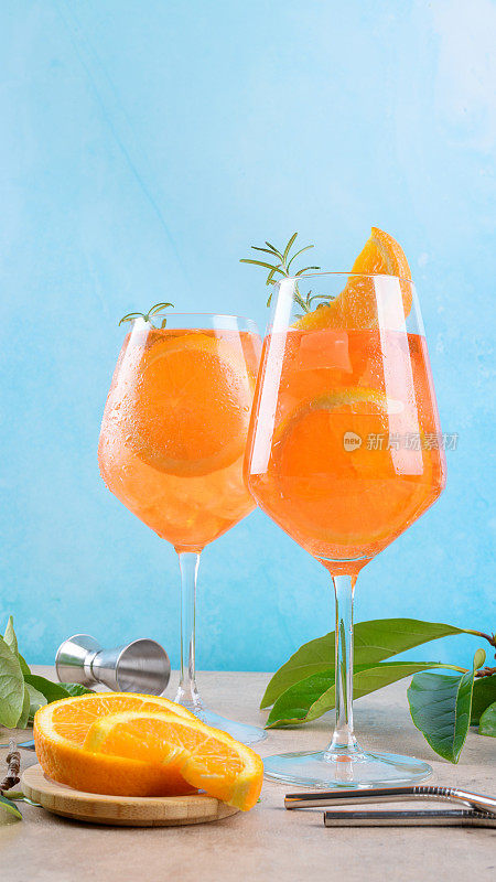 经典的意大利开胃酒，两杯加冰，蓝色背景的橙色，大理石平台