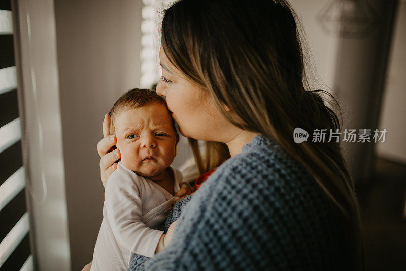 一位母亲在家里抱着并亲吻她刚出生的儿子