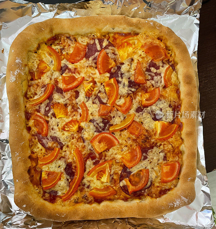 顶部视图热自制的松脆披萨装饰番茄，火腿，奶酪。