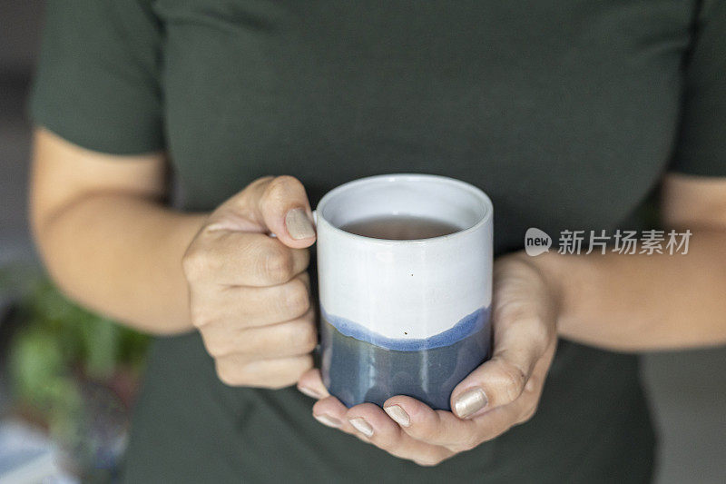 女性手捧陶瓷杯茶