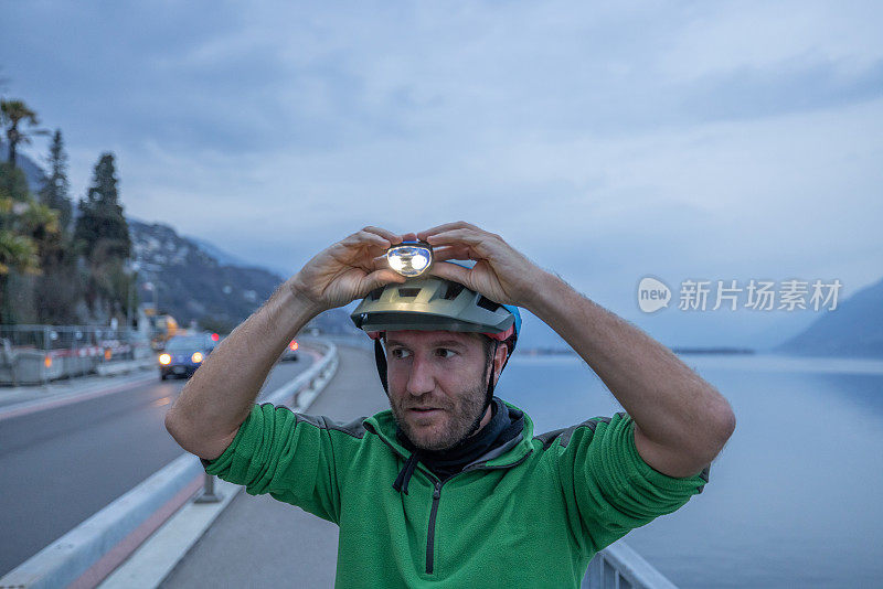 骑自行车的人调整头盔上的头灯，夜间户外健身