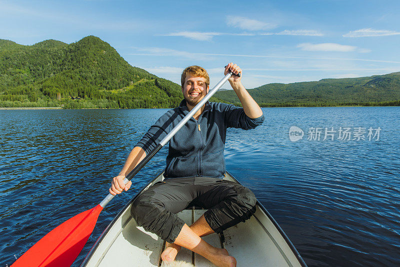 一个快乐的人在挪威风景优美的湖上划船