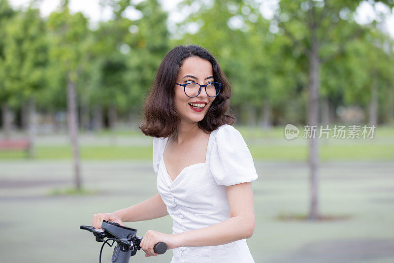 一位年轻女子在公园里骑着电动滑板车。