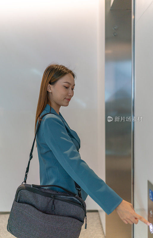 一天结束了。年轻的亚洲女商人背着笔记本电脑包准备离开办公室回家