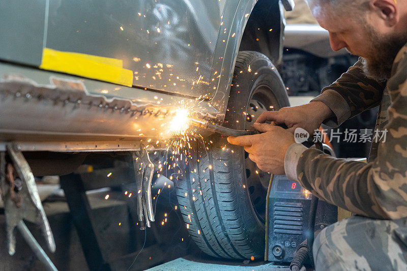 专业的汽车修理工用电焊机修理汽车。