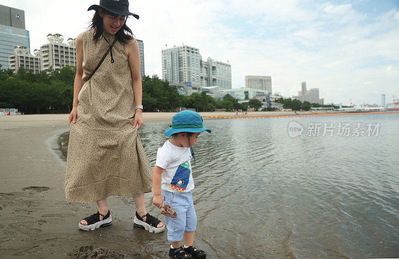 年轻的母亲带着她的小儿子在海滩上散步