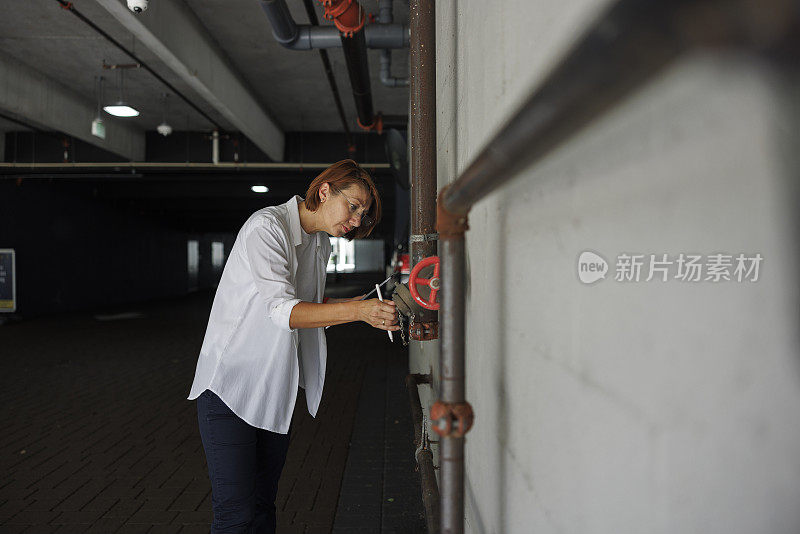 停车场灭火系统失灵。戴眼镜的红发女理赔员在室内停车场检查并登记灭火系统。