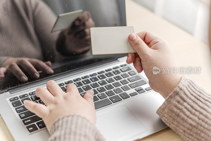 女性在家办公，使用笔记本电脑、智能手机和非接触式支付