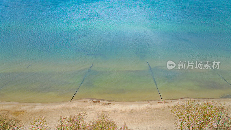 无人机拍摄的波兰西波美拉尼亚省吉斯基海滩。这张照片展示了波罗的海蓝绿色的海水、宽阔的沙滩和沙丘上光秃秃的树木。二月冬天被俘。