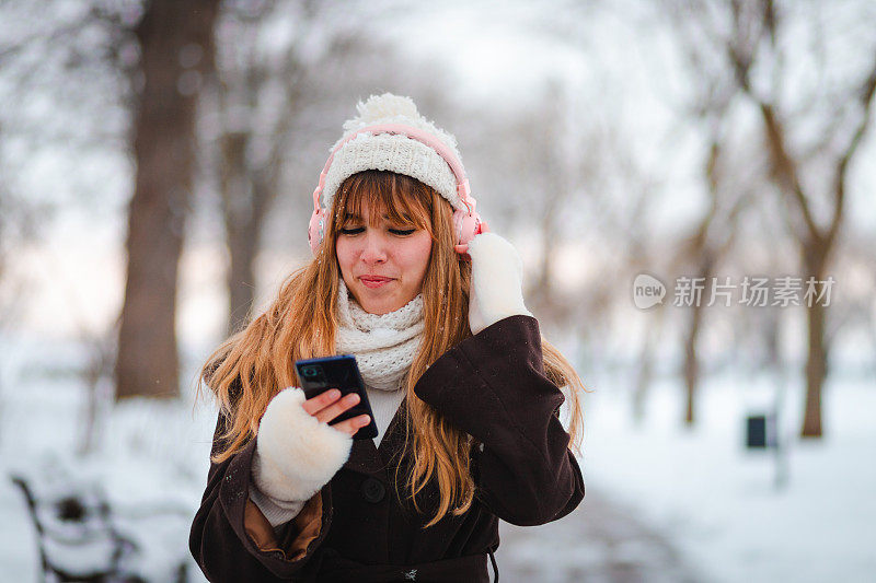 下雪的时候，一个快乐的年轻女子在公园里散步