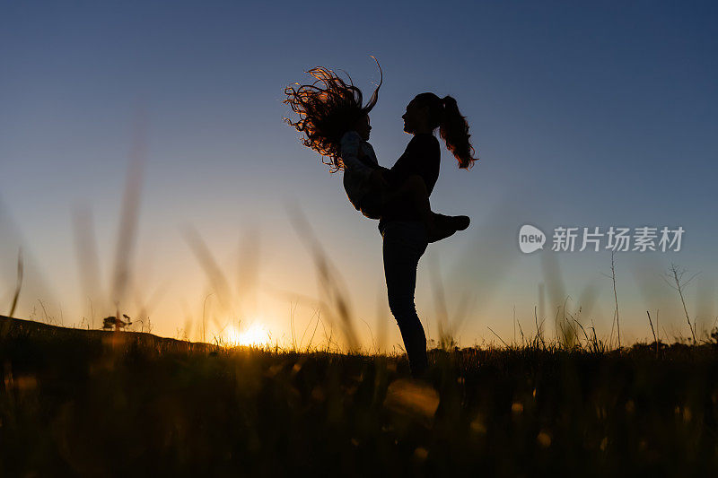 夕阳下田野里母亲抱着女儿的剪影