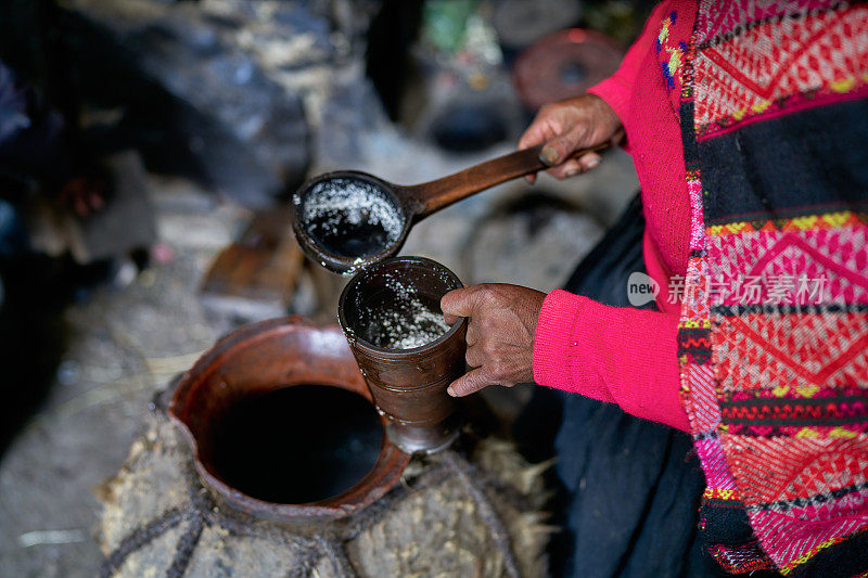 一名来自克丘亚克罗族的妇女将一种来自安第斯山脉的神圣而典型的饮料chica倒入一个粘土玻璃杯中。