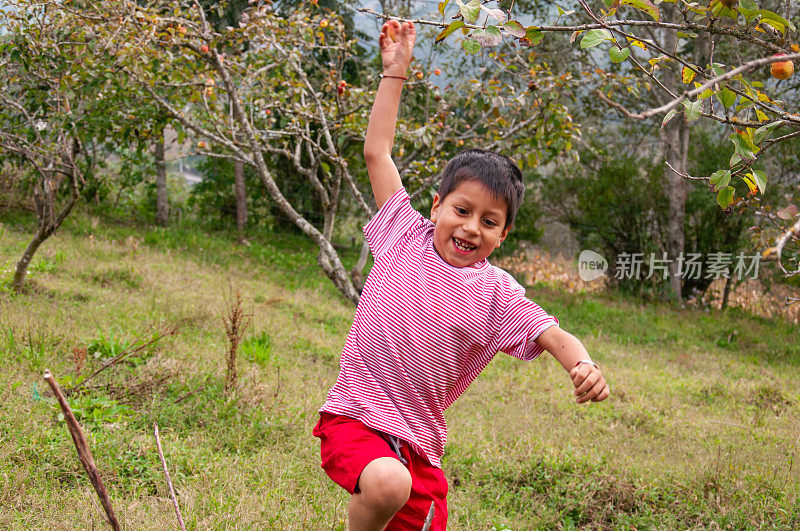 欢快的孩子伸开双臂在草地上奔跑，享受着户外的乐趣。