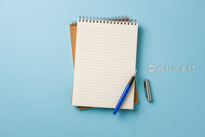 笔记本和钢笔在蓝色背景上的顶视图