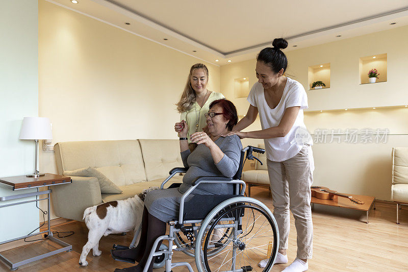 坐在轮椅上的老妇人正在享受她的两个女儿的来访。