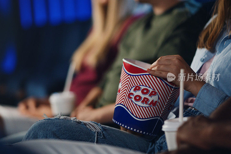 一个面目全非的年轻女人拿着爆米花在电影院看电影。