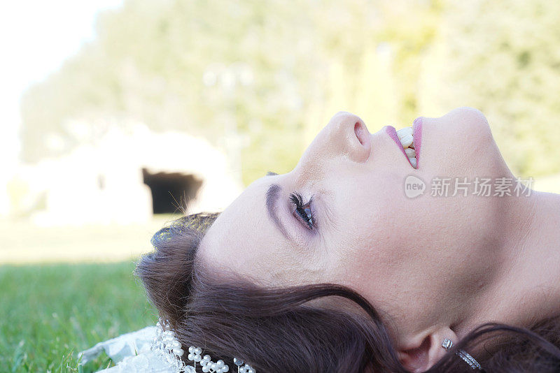 新婚夫妇的婚礼。新娘躺在草地上。美丽的新娘，长长的面纱和时尚的妆容。在婚礼之前