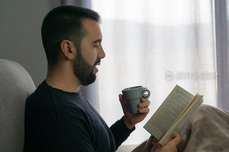 男人一边喝咖啡一边看书