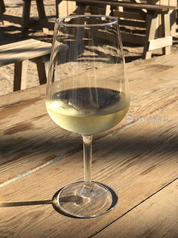 木桌上放着一个盛满白葡萄酒的玻璃杯