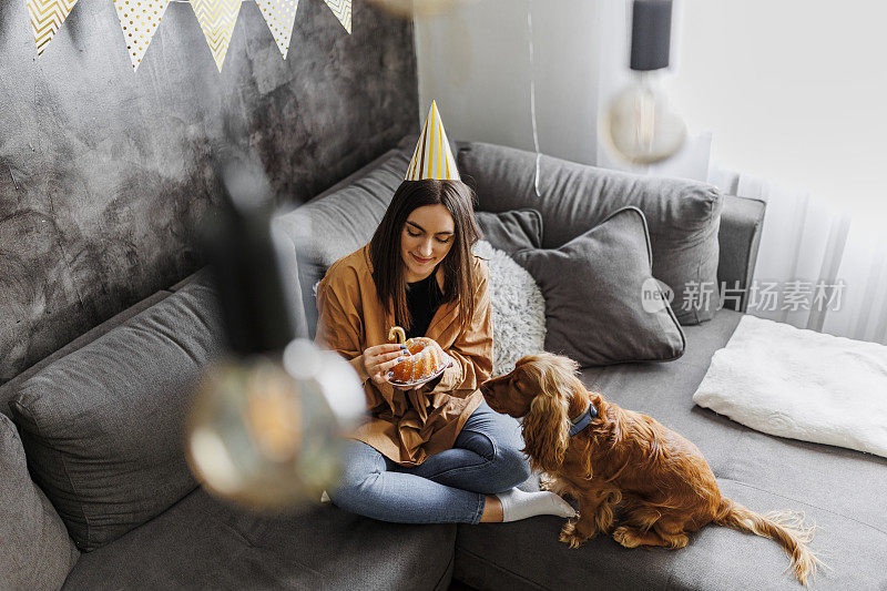 微笑的女人和她的狗在家里庆祝她的狗生日。